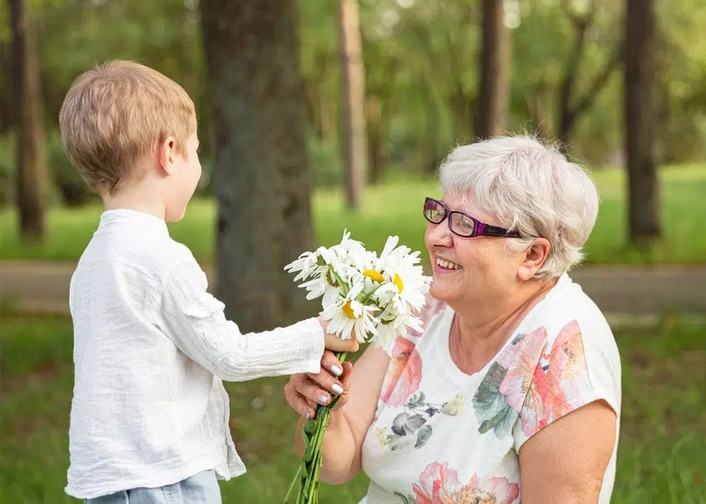 little boy giving flowers to senior woman