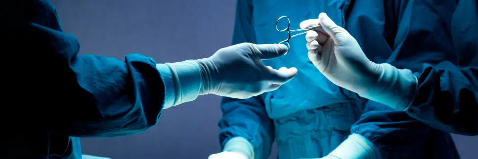 Surgical professionals hand a tool from one person to anther