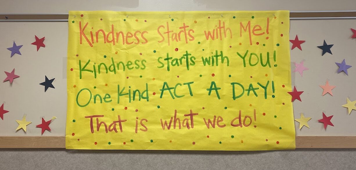 A sign made of paper that says. "Kindness starts with me, Kindness stars with you, One Kind Act a Day, that is what we do"