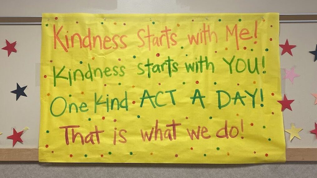 A sign made of paper that says. "Kindness starts with me, Kindness stars with you, One Kind Act a Day, that is what we do"