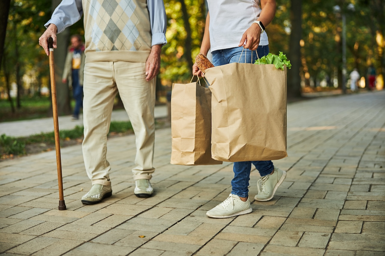 woman helping elderly man carry groceries