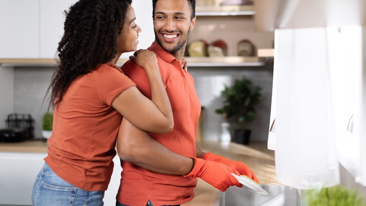 Couple smiling while doing dishes together, showing the importance of kindness in everyday relationships