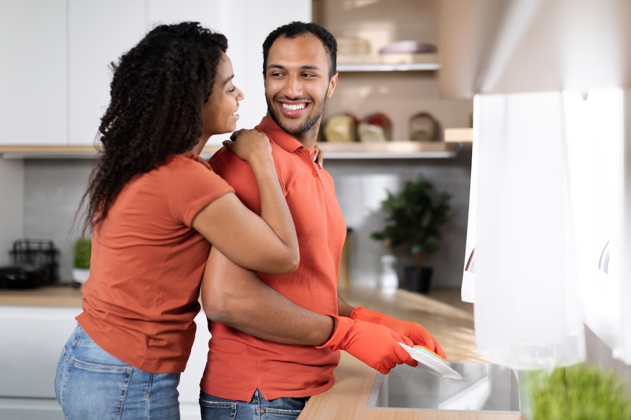 Couple smiling while doing dishes together, showing the importance of kindness in everyday relationships